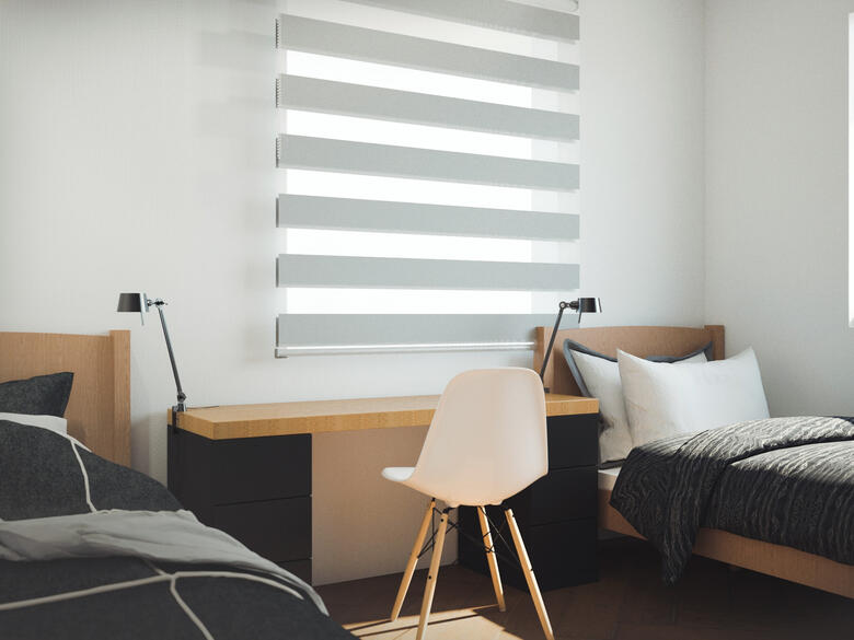 Two beds flushed agains the wall in grays and warm wood, with a study table in the middle with a green Eames chair.